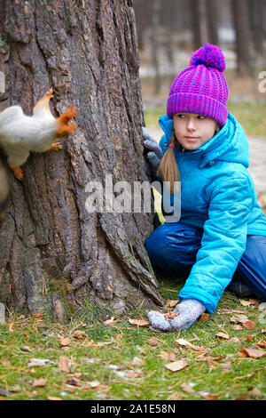 Girl feeding red squirrel in the autumn forest Stock Photo