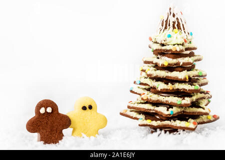 Christmas tree and little man cookies standing in the snow, white background with copyspace Stock Photo