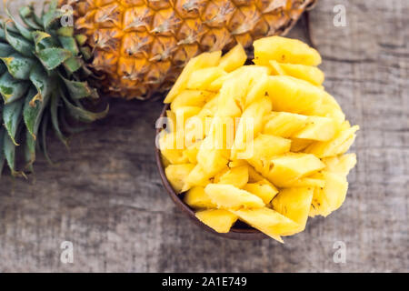 Pineapple slices and pineapple shelled Asian-style on the old wooden background. Tropical fruit concept. Stock Photo