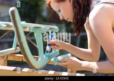 old wooden sledge is getting painted with chalky paint in blue and white, shabby chic finish Stock Photo