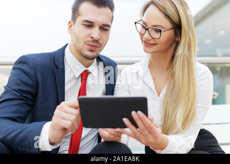 Successful young businesspeople analyzing financial situation on digital tablet indoors Stock Photo