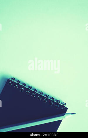 Dark blue notebook, a blue pensil on trendy mint background. Back to school concept. Mock up, flat lay. Stock Photo