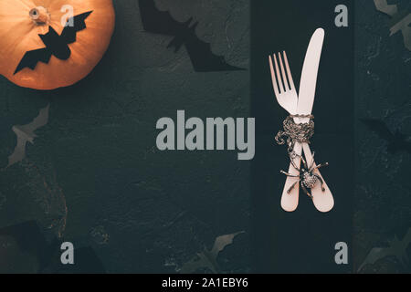 Photo of halloween pumpkin, knife, fork, bat on black table Stock Photo