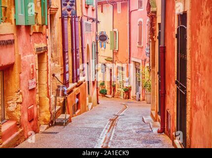 A narrow street in the beautiful French village of Roussillon, where the buildings are made of locally mined ochre and it is said that there are 17 di Stock Photo