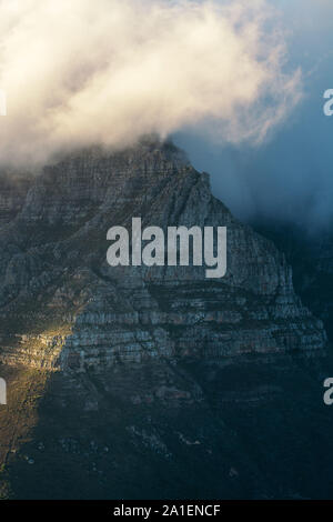 Table Mountain in Cape Town, South Africa covered by clouds commonly know as the table cloth as seen from the top of Lion's head mountain at sunrise Stock Photo