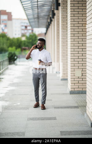 Positive indu student in casual wear watching funny video and messaging with friends in online chat on mobile phone using 4G internet connection stand Stock Photo