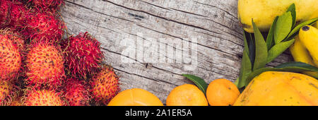 BANNER, Long Format Colorful fruits on the white wooden table, Bananas, carambola, mango, papaya, mandarin, rambutan, pamela, copy space for text Stock Photo