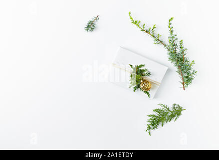 Christmas present decorated with evergreen twigs on white background. Flatlay. Copy space Stock Photo