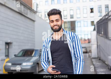 Modern arab young man with mobile phone in the street. Outdoor portrait Stock Photo