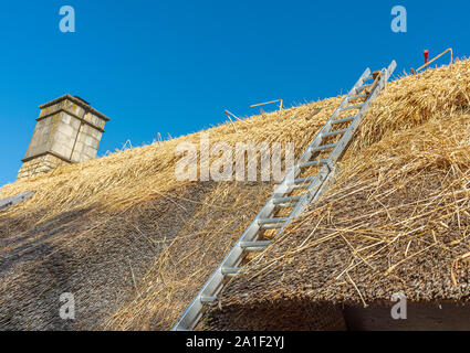 Tools on the roof of a thatched village cottage as it is being repairing and renewing Stock Photo