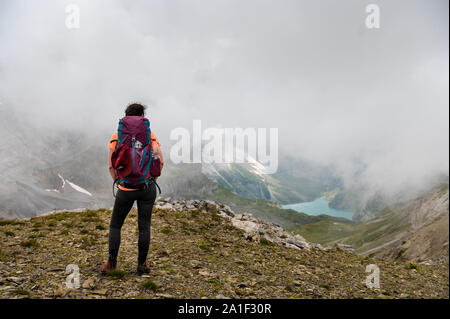 hiking girl at Hohtürli with Oeschinensee in the distance in misty clouds while hiking Stock Photo