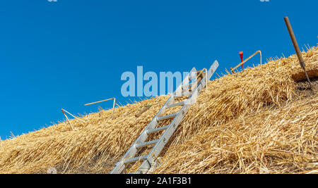 Tools on the roof of a thatched village cottage as it is being repairing and renewing Stock Photo