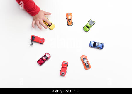 Child chooses his favourite toy car from selection of toys Stock Photo