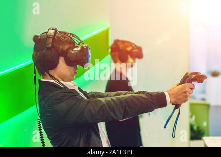 Young man playing video games virtual reality glasses. Cheerful man having fun with new trends technology - Gaming concept. Stock Photo