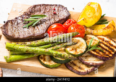 Beef steak grilled with vegetables on white stone table. Stock Photo