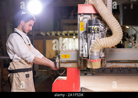 furniture factory, Small-Sized Companies and people concept - Serious concentrated handsome bearded worker of furniture factory Stock Photo