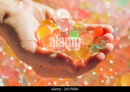 Colored balls of water beads, hydrogel in in hands. Sensory experiences. Stock Photo