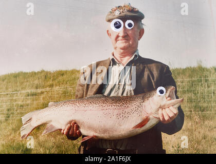 Funny picture of old man (not recognisable) holding big fish with googley eyes Stock Photo