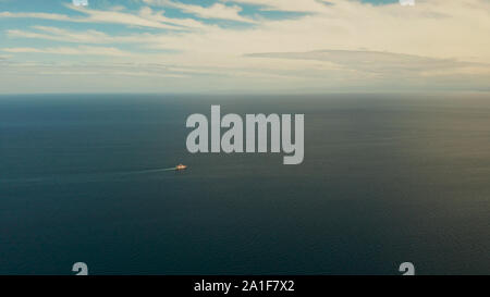 Small passenger ferry cruising in the open blue sea against blue sky with clouds, aerial view. Seascape: assenger ferry boat in open waters Philippines, Mindanao Stock Photo