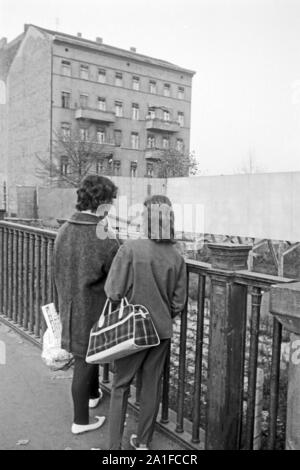Zwei Frauen stehen vor einem Sichtschutz an der Grenze des amerikanischen Sektors in Berlin, Deutschland 1962. Two women are standing in front of a blind at the border of the American sector in Berlin, Germany 1962. Stock Photo