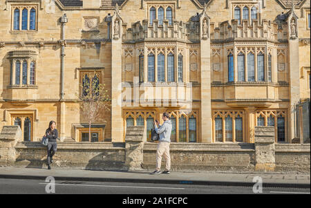 A male student takes a photo of a female student outside Magdalen college, university of Oxford, England. Stock Photo