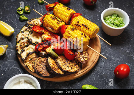 Assorted delicious grilled vegetables on a dark stone background. Summer food barbecue. Stock Photo