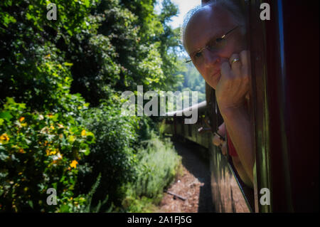 A tourist passenger traveling in a open train car looks at the passing scenery as the train travels though the Nantahala National Forest in North Carol Stock Photo