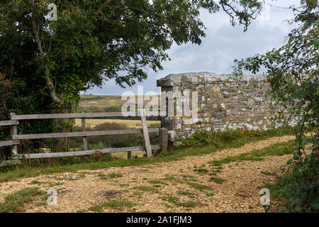 Rural scene of a stone bridge wall and wooden fence along a quiet pathway in Dorset, United Kingdom Stock Photo