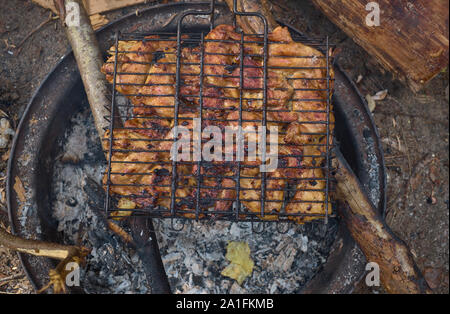 Shashlik or shashlyk preparing on a barbecue grill over charcoal. Grilled cubes of pork meat on metal skewer. Meat on skewers is roasted on fire Stock Photo