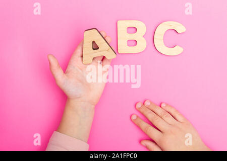 ABC letters in child's hands on pink background. Stock Photo