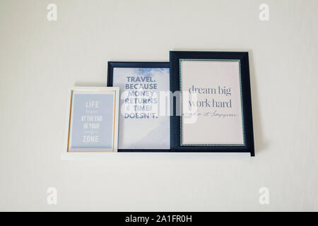 Frames with motivational and inspirational quotes about put on shelf. Interior design. Home decor Stock Photo