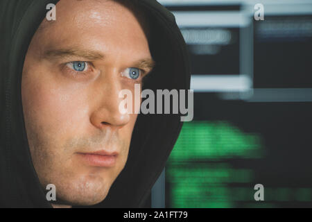 Handsome hacker in black hoodie. Hacking and internet security concept. Stock Photo