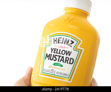 Photo of a man holding a yellow mustard from Heinz brand with white stúdio background. Stock Photo