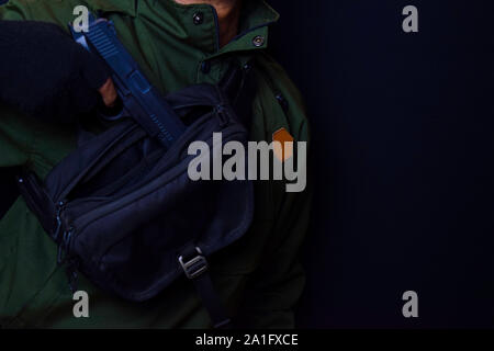 asian man holding a gun. Gun in his hand background of a waist bag Stock Photo