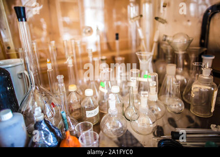 Glass bottles, test tubes, flasks and cups are on the table in an old chemical laboratory Stock Photo