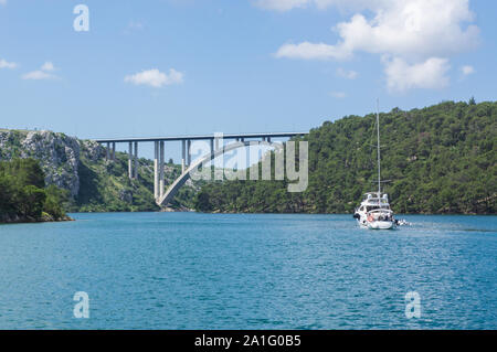 A boat approaches a bridge in the Croatian coastal waters. Stock Photo