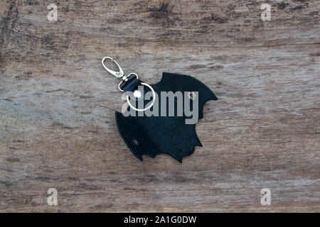 Leather keychain in Bat shape and old key in wooden door. - image Stock Photo