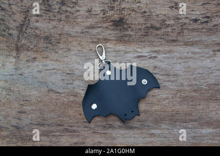 Leather keychain in Bat shape and old key in wooden door. - image Stock Photo