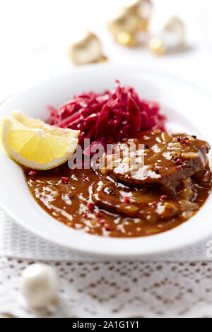 Pork roast with onion-mushroom sauce and red cabbage seeds for Christmas Stock Photo