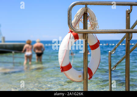 Emergency lifebuoy hanging on fence near sea at beach Stock Photo