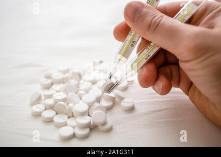 man is going to eat the drug tablets and holds two medical thermometer like chopsticks Stock Photo