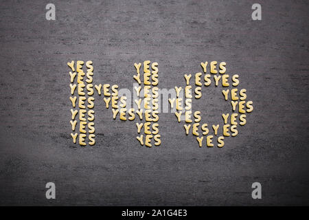 The answer  'no' made up of a set of words 'yes', with small pasta letters on a dark background of a wooden board, showing the hidden meaning and ambi Stock Photo