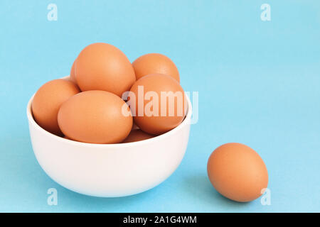 Fresh brown hen's eggs  in the white bowl on light blue background Stock Photo