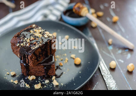 Closeup of a plate of fresh homemade brownies with hazelnuts on a striped napkin and wooden table. Stock Photo