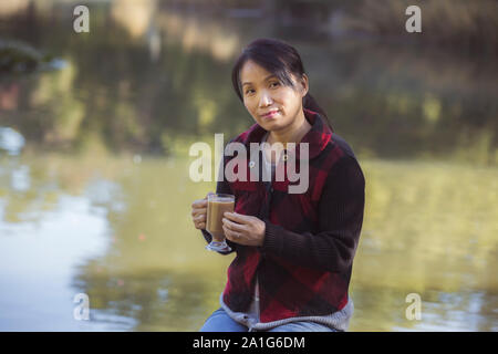 A korean woman enjoys a cup of coffee on a fall day in Spokane, Washington. Stock Photo