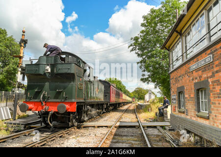 CRANMORE, ENGLAND - JULY 2019: Steam engine fireman climbing on the coal tender of the locomotive at Cranmore Station on the East Somerset Railway. Stock Photo