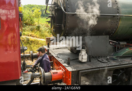 CRANMORE, ENGLAND - JULY 2019: Steam train worker coupling a steam engine to a carriage at Cranmore Station on the East Somerset Railway. Stock Photo