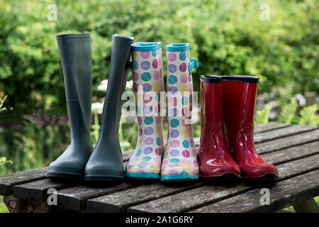 Muddy adults and kids wellington boots on an old picnic table Stock Photo