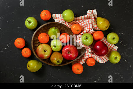 Fat lay photo - colourful fruits - apples, pears and tangerines on black marble like board Stock Photo