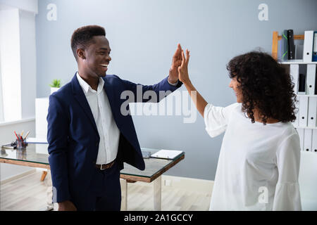 Businessman Giving High Five To His Colleague At Work Stock Photo